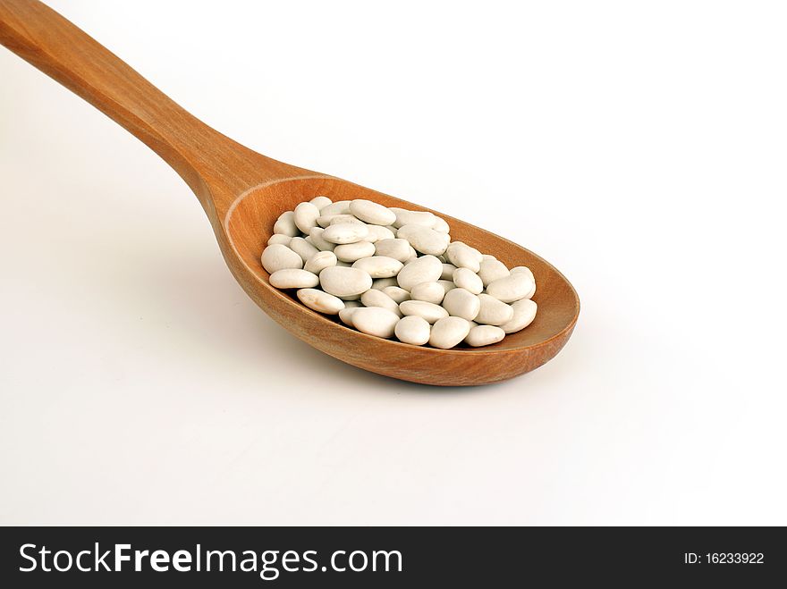 Top view of wooden spoon full of white beans