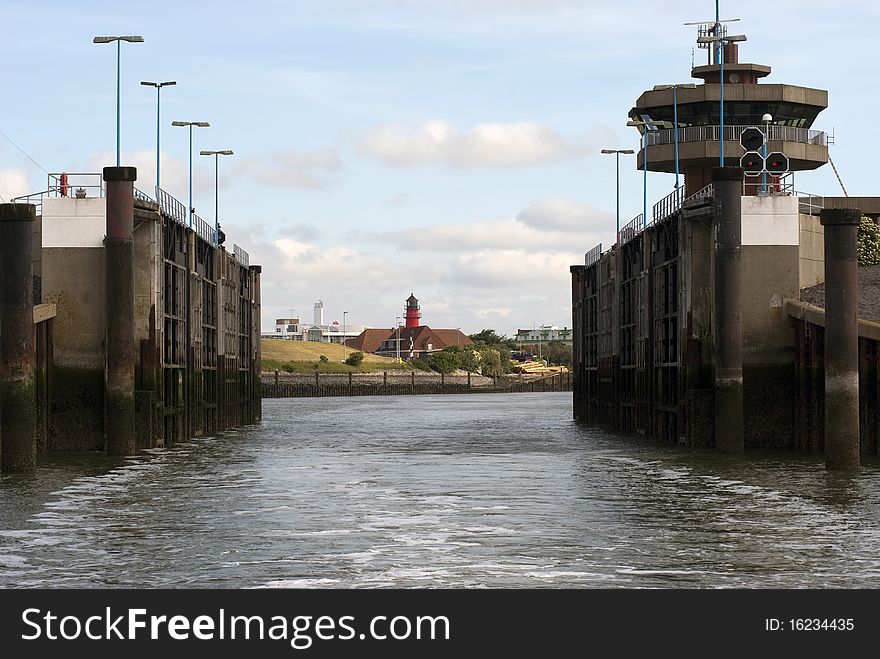 Open lock gate, lighthouse and small town in the background.