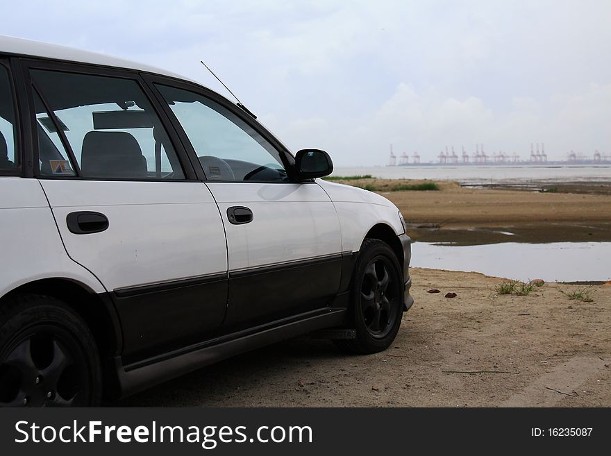 A car parked in front of a container terminal. A car parked in front of a container terminal