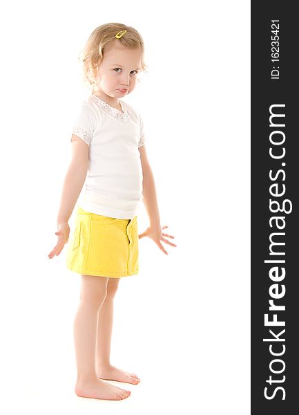 Fretful little girl wearing a yellow skirt standing on white background. Fretful little girl wearing a yellow skirt standing on white background