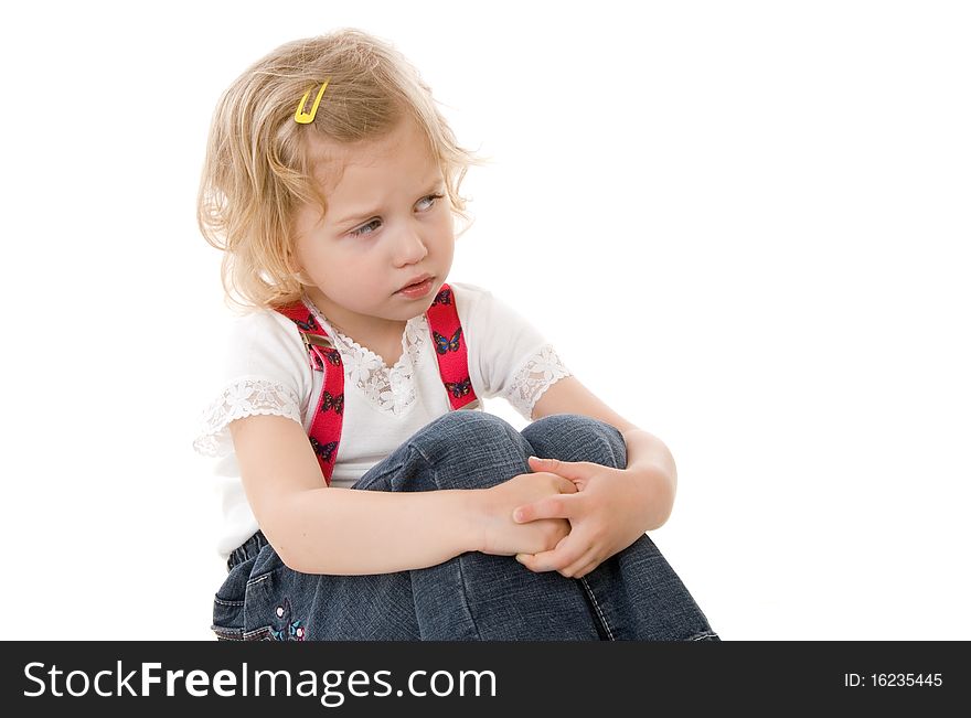 Sad little blond girl in red suspenders sitting on white background