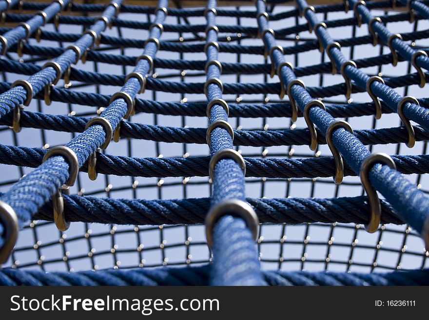 Big blue ropes in perspective, in a playground, for children, together by a hook, one rope in detail at the front. Big blue ropes in perspective, in a playground, for children, together by a hook, one rope in detail at the front