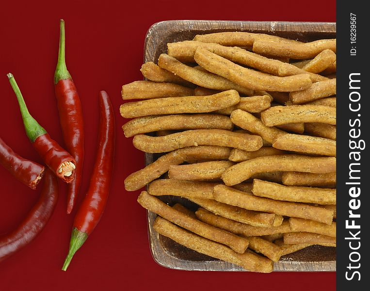 Chilli and sticks on red background. Chilli and sticks on red background