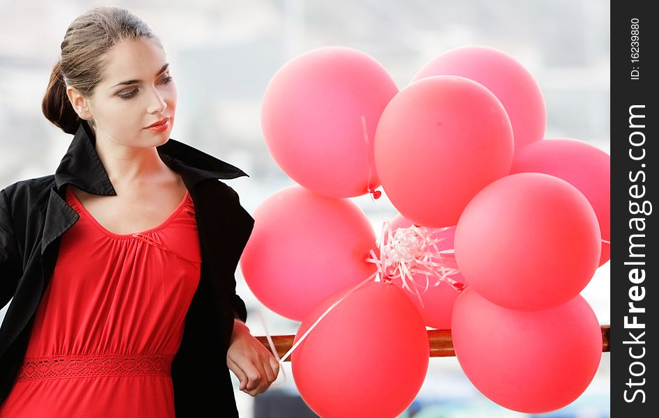 Outdoor portrait of upset young woman with red balloons