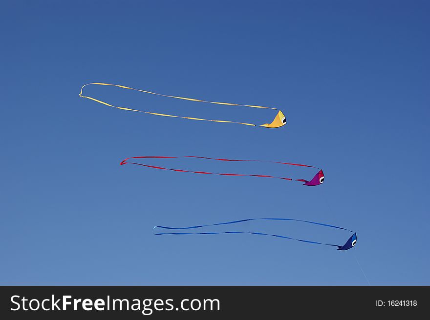 Three fish-shaped kites against a vivid blue sky. Three fish-shaped kites against a vivid blue sky.