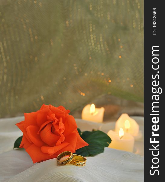 Gold wedding bands with candles and orange rose. Gold wedding bands with candles and orange rose