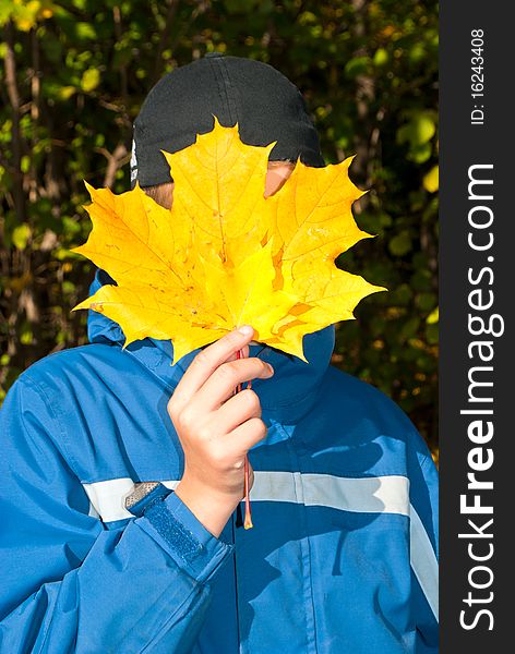 The teenager on a background of yellow sheets of a maple. Solar autumn.