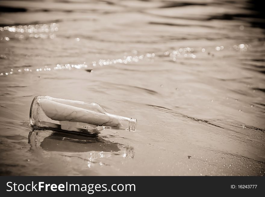 A Glass bottle with a letter washed up on a sandy beach. A Glass bottle with a letter washed up on a sandy beach