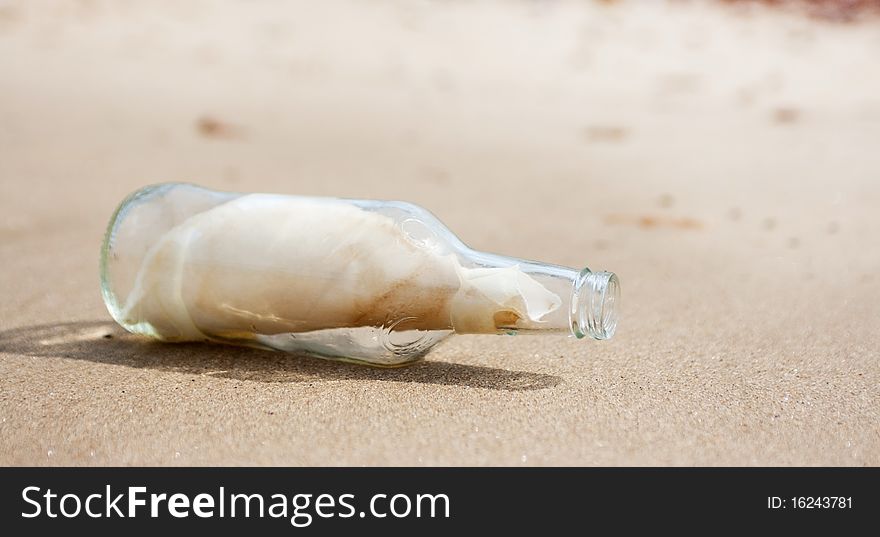 A clear glass bottle with a message on sand. A clear glass bottle with a message on sand