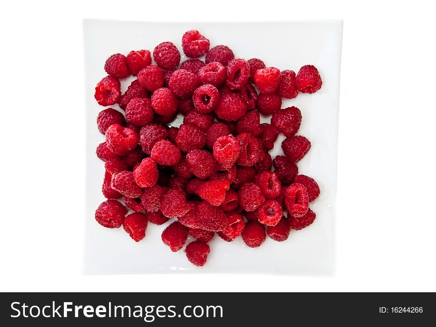 A heap of red raspberries on plate. Isolated on white