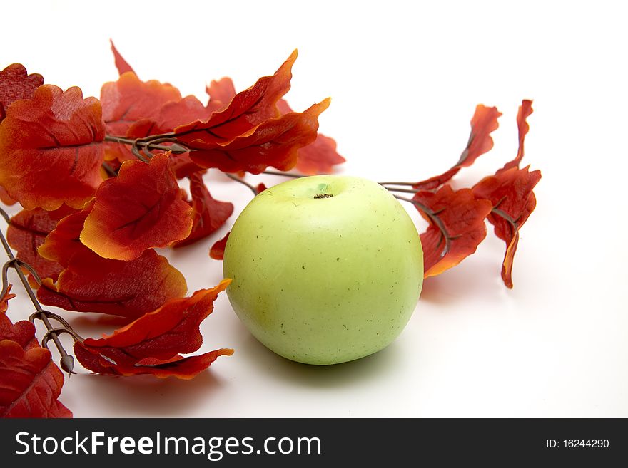 Artificial branch with red leaves and apple