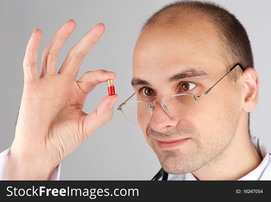 Young doctor looking at pill