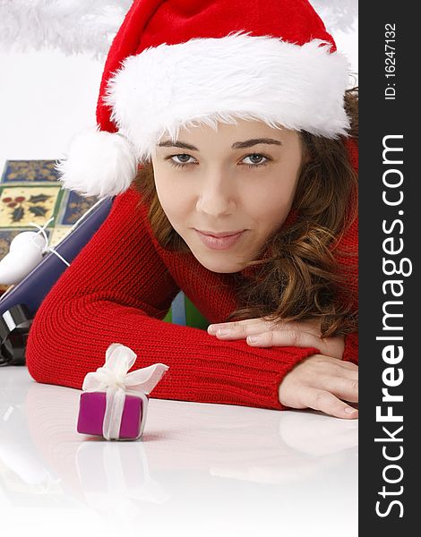 Beautiful young woman wearing santa hat next to christmas gift on white background