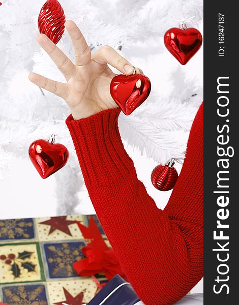 Hand holding a christmas heart near to a christmas tree