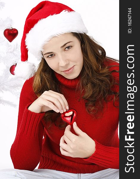 Beautiful young woman wearing santa hat holding a christmas heart