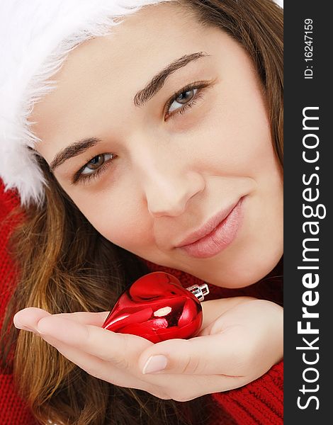 Beautiful young woman wearing santa hat holding a christmas heart