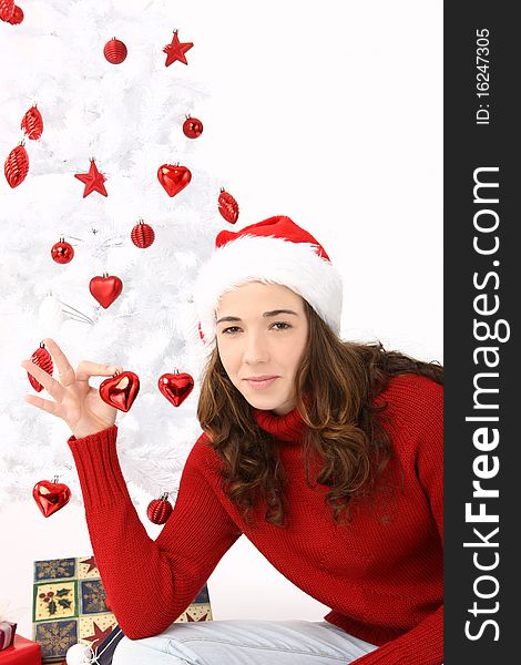 Beautiful young woman wearing santa hat holding an heart