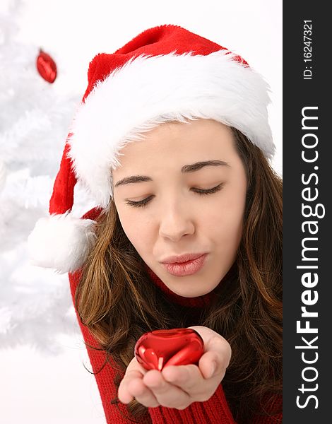 Beautiful young woman wearing santa hat holding an heart