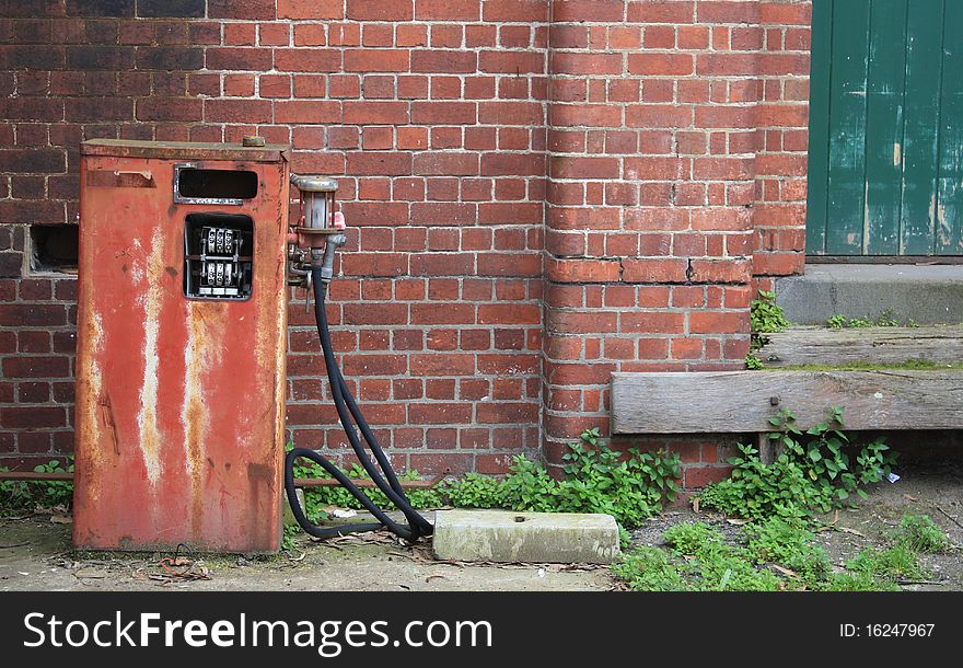 Rusty old petrol bowser and brick wall