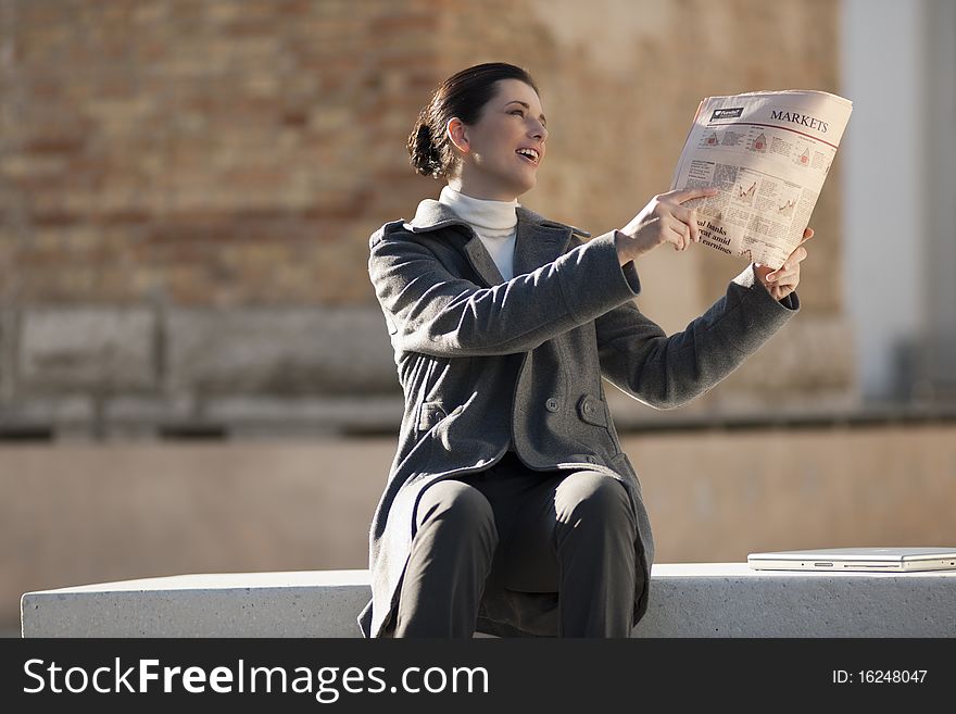 Young woman reading newspaper outdoors