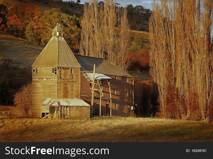 An old barn used for storing and curing hops (oasthouse) in golden light at sunset near New Norfolk in Tasmania. An old barn used for storing and curing hops (oasthouse) in golden light at sunset near New Norfolk in Tasmania