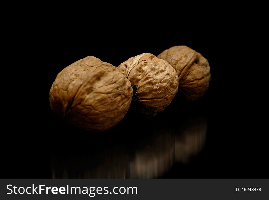 Three nuts with reflection. Black background.