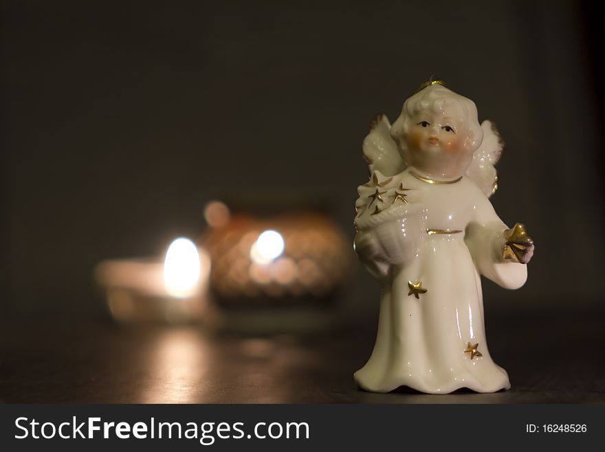 White china christmas angel with golden stars and candles in the night