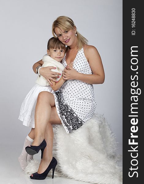 Full length portrait of two, beautiful young mother hugging her little daughter, studio image. Full length portrait of two, beautiful young mother hugging her little daughter, studio image