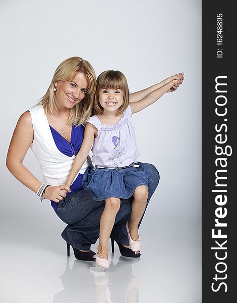 Full length portrait of two, young pretty mother and cute little daughter, smiling, studio image. Full length portrait of two, young pretty mother and cute little daughter, smiling, studio image