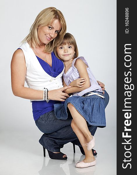 Full length portrait of two, beautiful young mother and daughter, smiling, studio image. Full length portrait of two, beautiful young mother and daughter, smiling, studio image