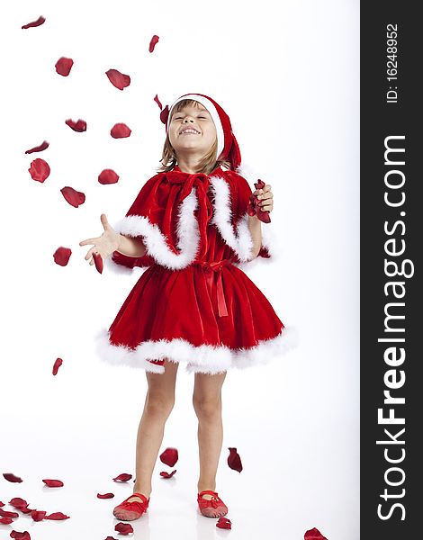 Full length portrait of a little Miss Santa or Santa's helper, joyful about a rain of rose petals. Studio image. Full length portrait of a little Miss Santa or Santa's helper, joyful about a rain of rose petals. Studio image