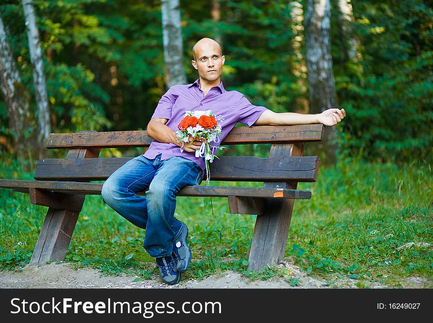 Photo of handsome guy with bouquet waiting for his girlfriend outside