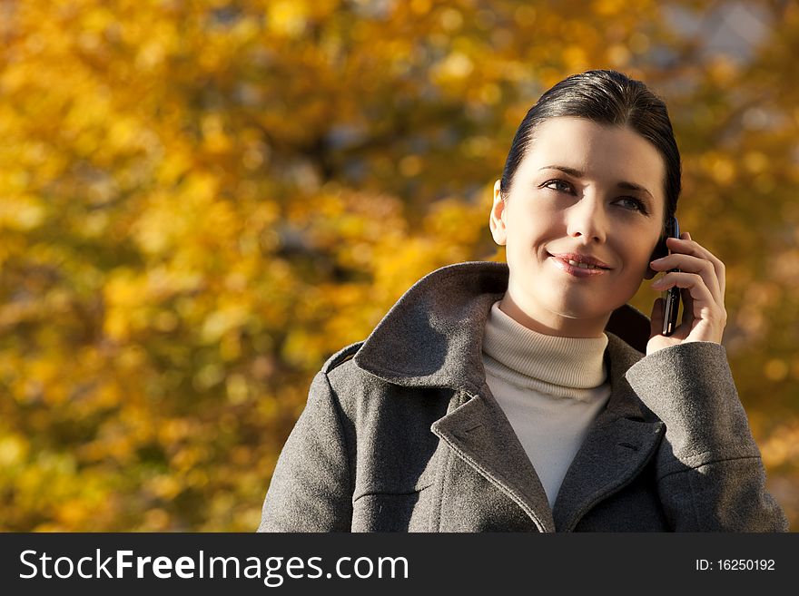 Young woman on the mobile phone, autumn background