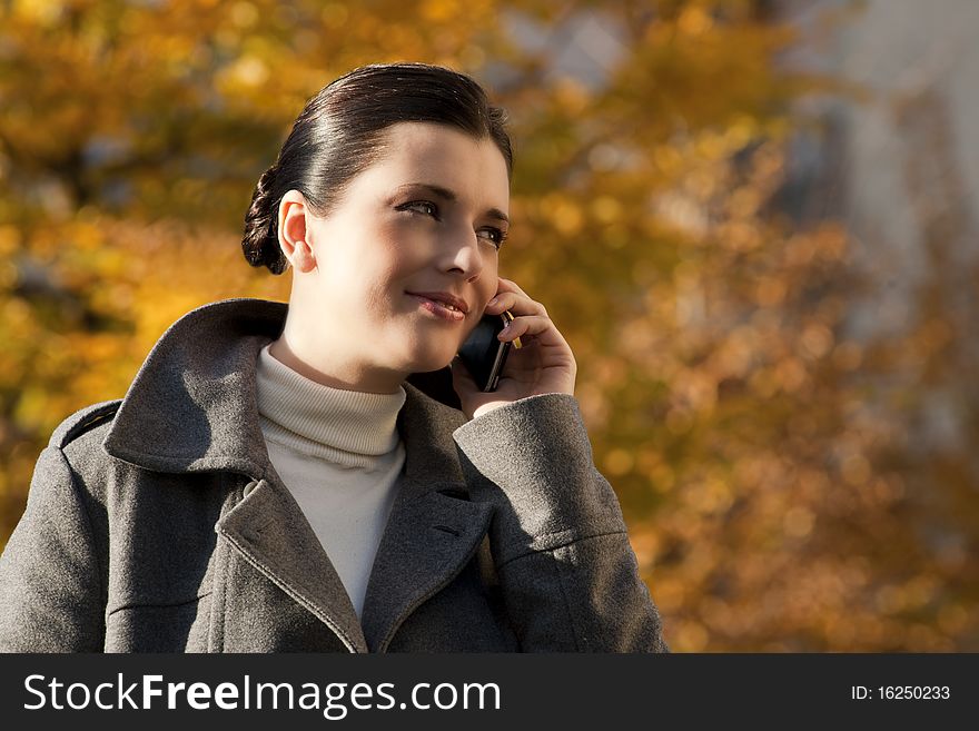 Young woman on the mobile phone, autumn background