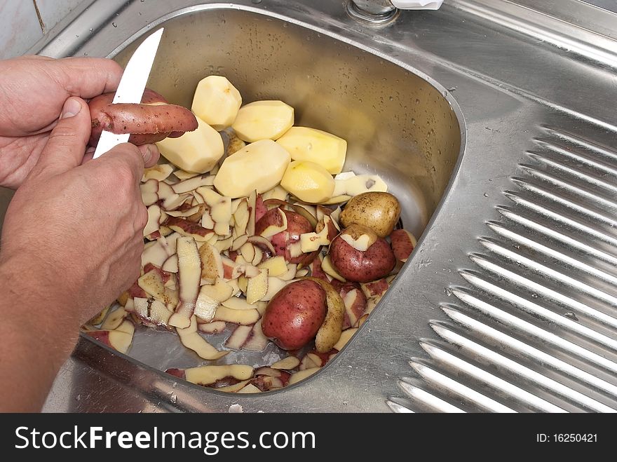 Men's hand peeling potatoes with knife