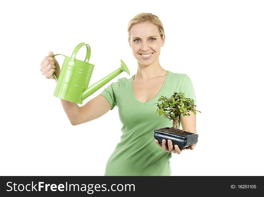 Young woman watering a bonsai tree; concepts: giving life, the beginning