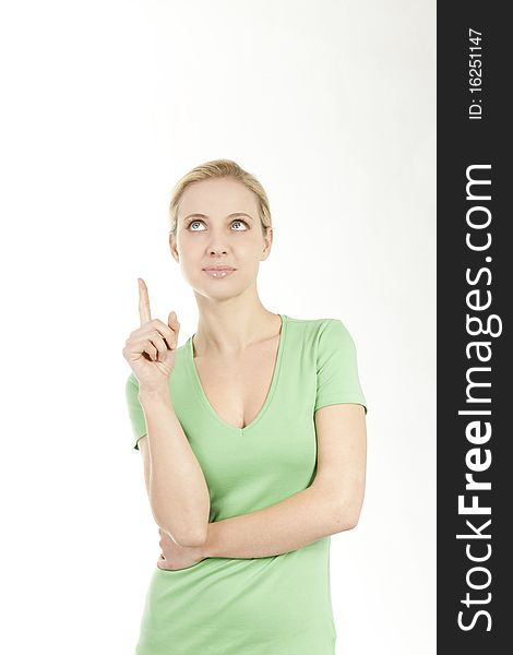 Young woman pointing at copy space; she is green dressed, maybe pointing at something concerned with nature and environment