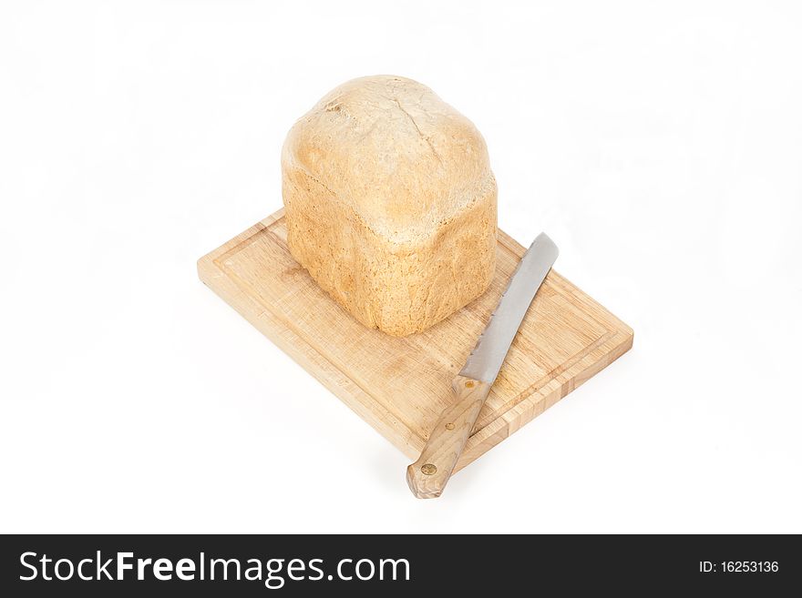 An angled studio view of a loaf of homemade bread on a wooden breadboard with a bread knife. An angled studio view of a loaf of homemade bread on a wooden breadboard with a bread knife.