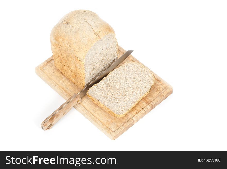 A top angled studio view of a loaf of homemade bread and a slice on a wooden breadboard with a bread knife. A top angled studio view of a loaf of homemade bread and a slice on a wooden breadboard with a bread knife.