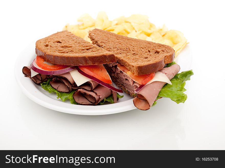 Delicious roast beef sandwich platter with whole wheat bread and potato chips. Delicious roast beef sandwich platter with whole wheat bread and potato chips