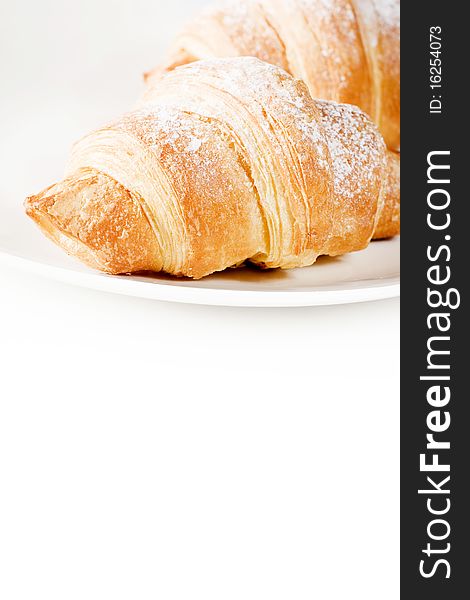 Fresh croissants on white plate with empty space below .