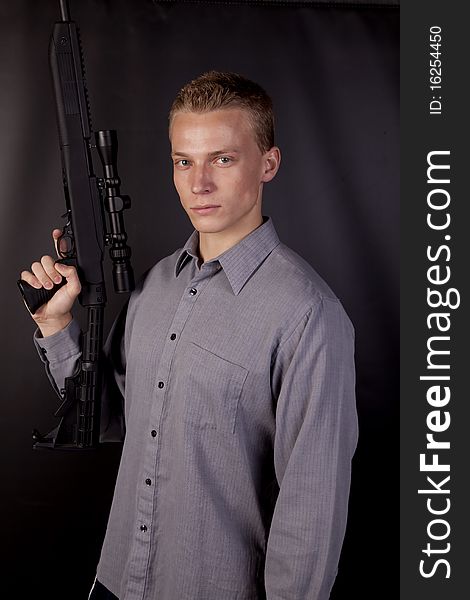 A man holding a gun with a serious expression on his face. A man holding a gun with a serious expression on his face.