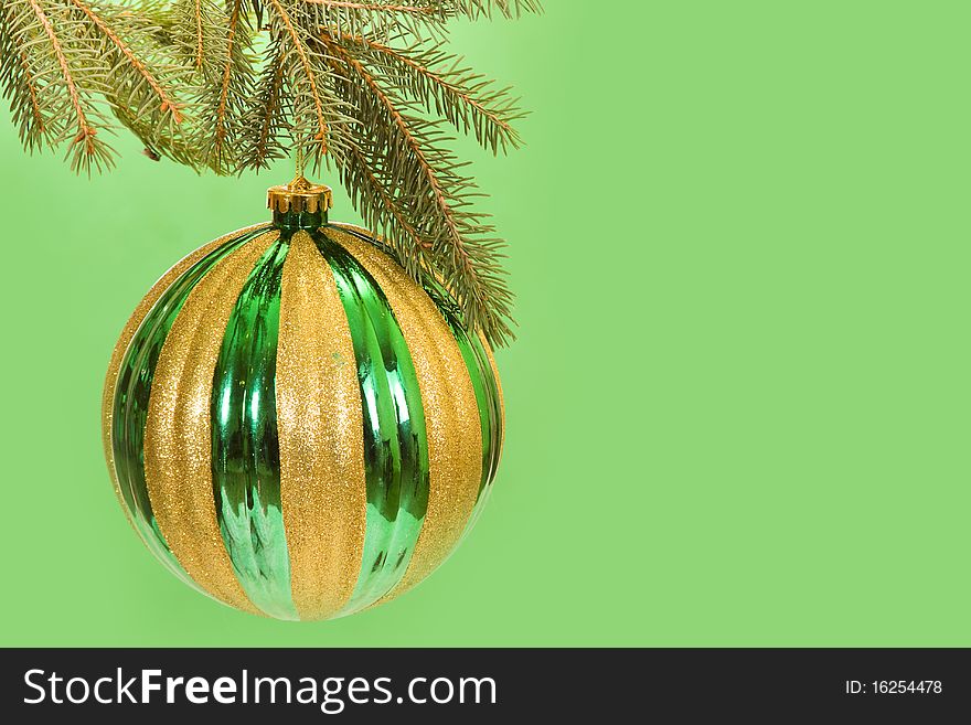 Christmas decoration ball hanging from a tree branch on a bright green background.
