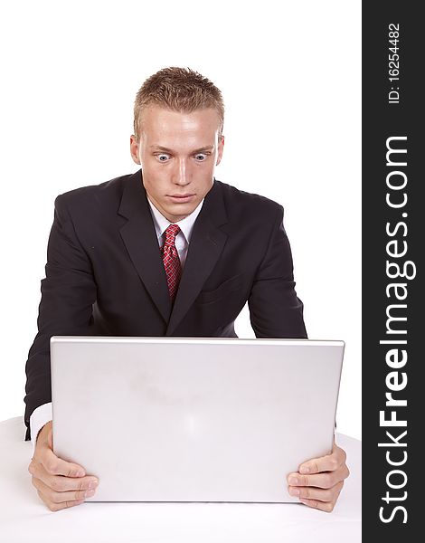 A young businessman sitting at his computer with a serious expression on his face. A young businessman sitting at his computer with a serious expression on his face.