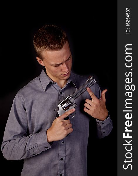 A young man looking down at his pistol in his hands. A young man looking down at his pistol in his hands.