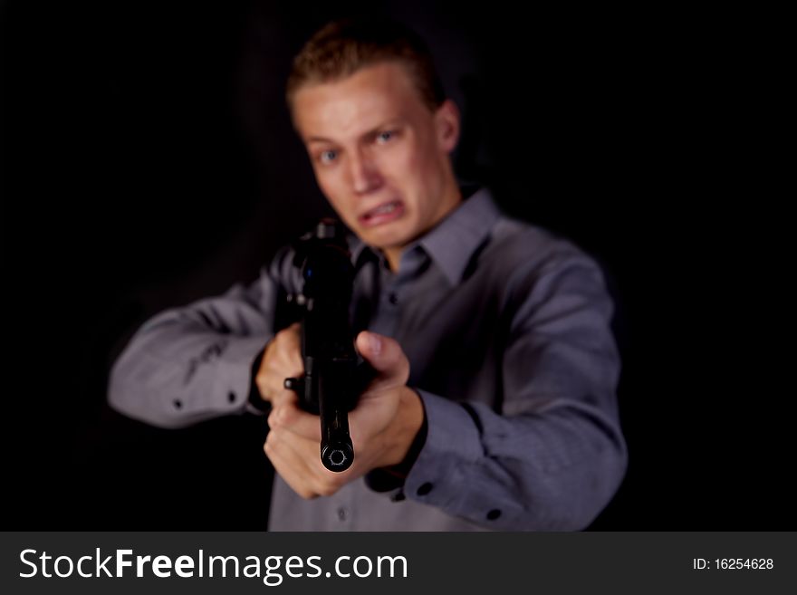 A young man pointing his gun at the camera with a scared expression on his face. A young man pointing his gun at the camera with a scared expression on his face.