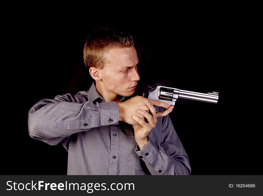 A young man pointing his gun with a black background. A young man pointing his gun with a black background.