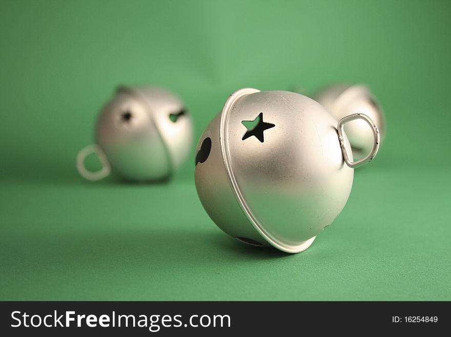 A collection of silver bells on a green background. A collection of silver bells on a green background