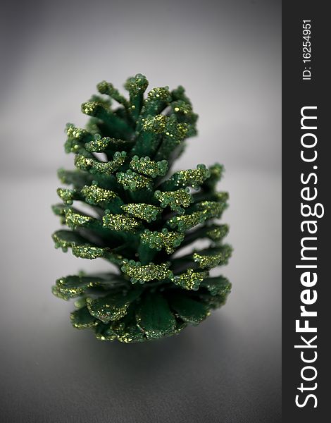 A glittery green pinecone on a silver background. A glittery green pinecone on a silver background