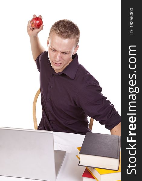 A young man sick of what is happening on his computer he is getting ready to throw his apple at the screen. A young man sick of what is happening on his computer he is getting ready to throw his apple at the screen.